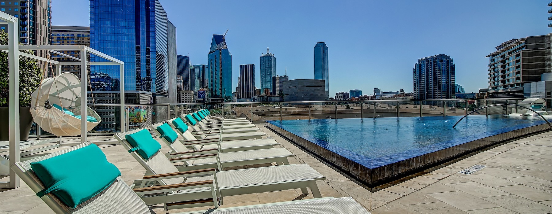 a pool with lounge chairs and a city skyline in the background