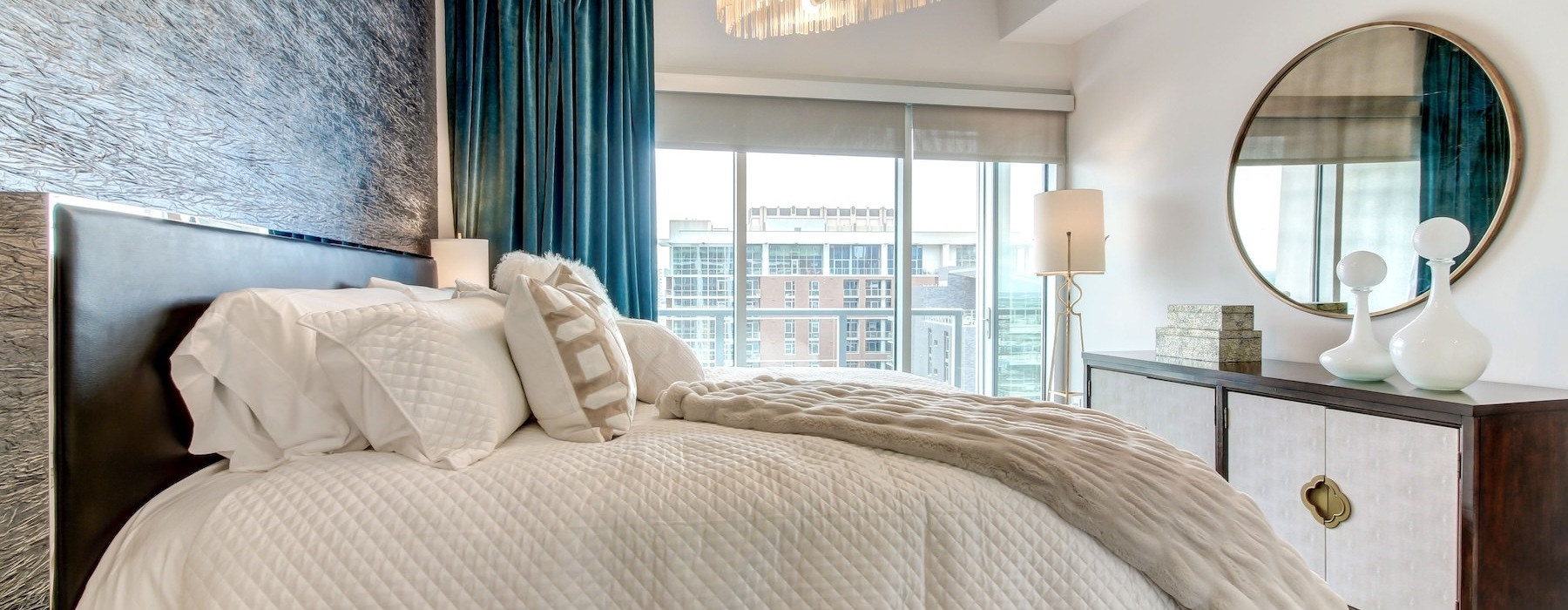 a bed with a large mirror and a chandelier